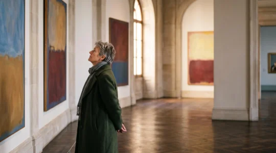 Visiteur contemplant avec émotion des œuvres abstraites dans une grande salle de musée belge baignée de lumière naturelle